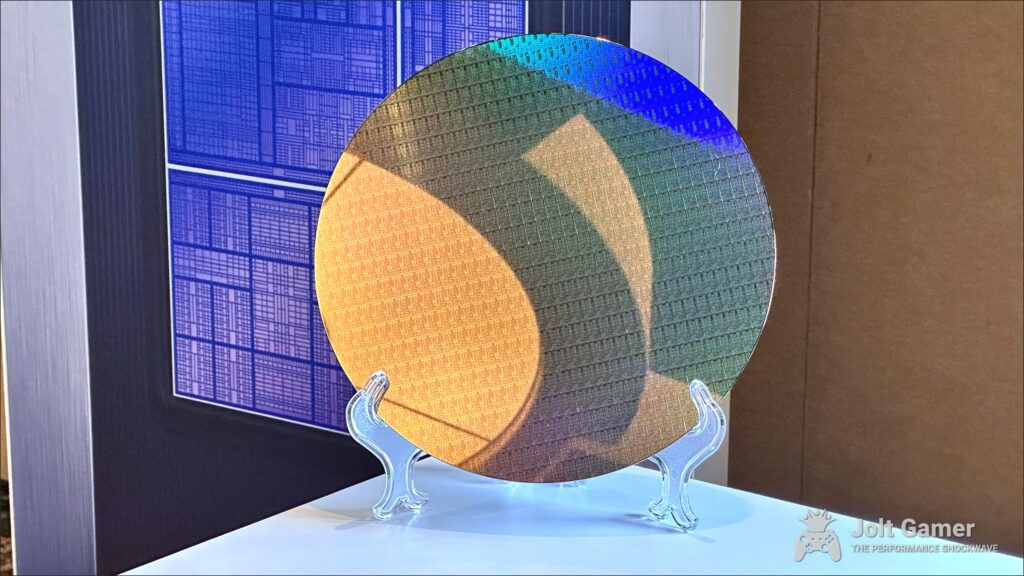 A photo of an Intel 18A wafer, full of Panther Lake compute tiles, with a stylized image of a complete PTL chip in the background.